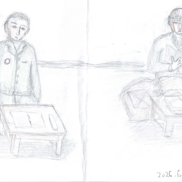 鉛筆と色鉛筆による線画。横長の紙の左右に、灰色の上着の人物が一人ずつ、低い木の机の前に座って正面を向く。左の人物は胸に赤い縁の丸いバッジを付け、机上に開いた冊子。右の人物は帽子をかぶり、両手で開いた本を持ち、膝の前に布団のような膨らみがあり、机上にも本と細長い物が置かれる。背景に水平の線が一本。右下に「2026.6.28」の書き込み。紙の中央に縦の折り目。