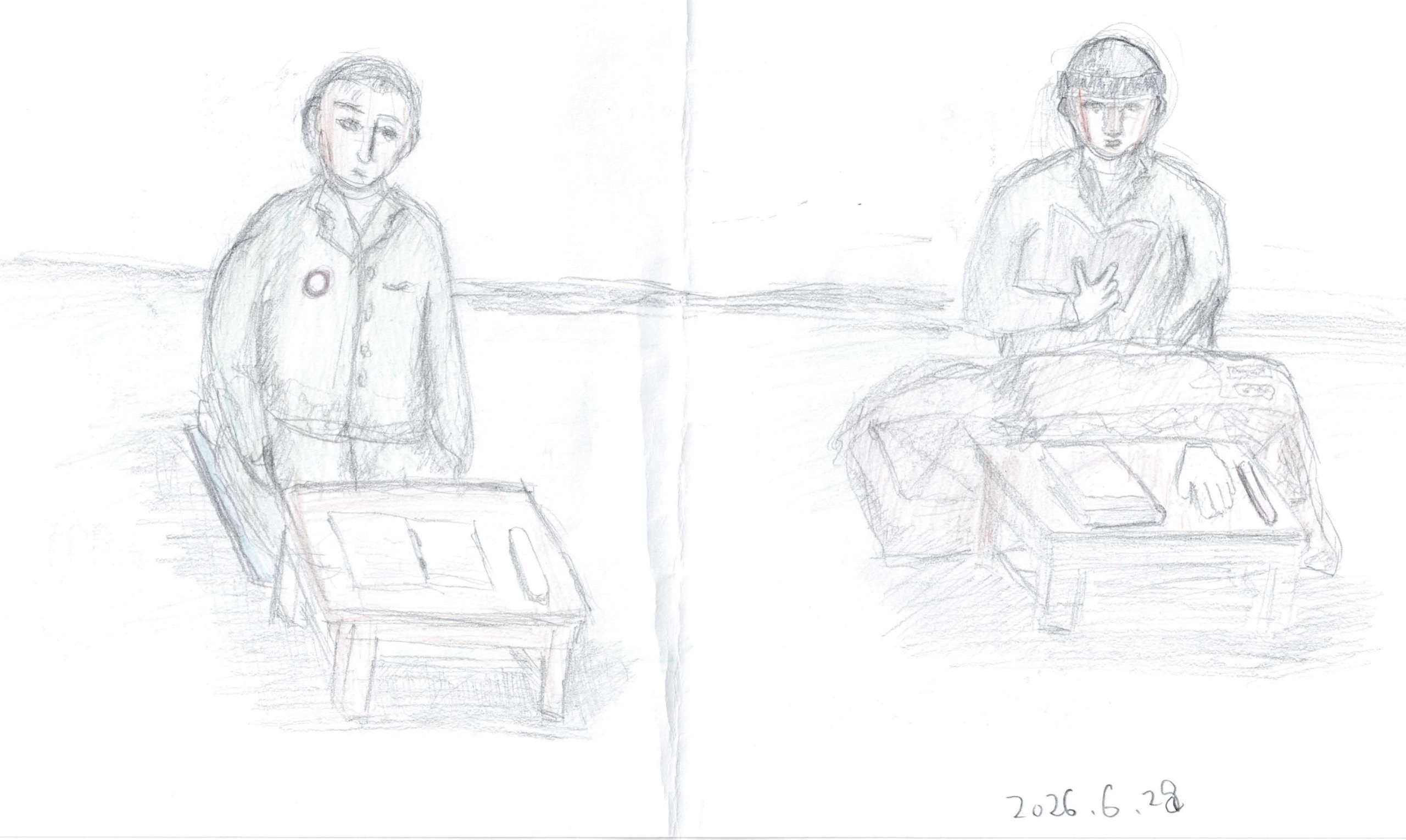鉛筆と色鉛筆による線画。横長の紙の左右に、灰色の上着の人物が一人ずつ、低い木の机の前に座って正面を向く。左の人物は胸に赤い縁の丸いバッジを付け、机上に開いた冊子。右の人物は帽子をかぶり、両手で開いた本を持ち、膝の前に布団のような膨らみがあり、机上にも本と細長い物が置かれる。背景に水平の線が一本。右下に「2026.6.28」の書き込み。紙の中央に縦の折り目。