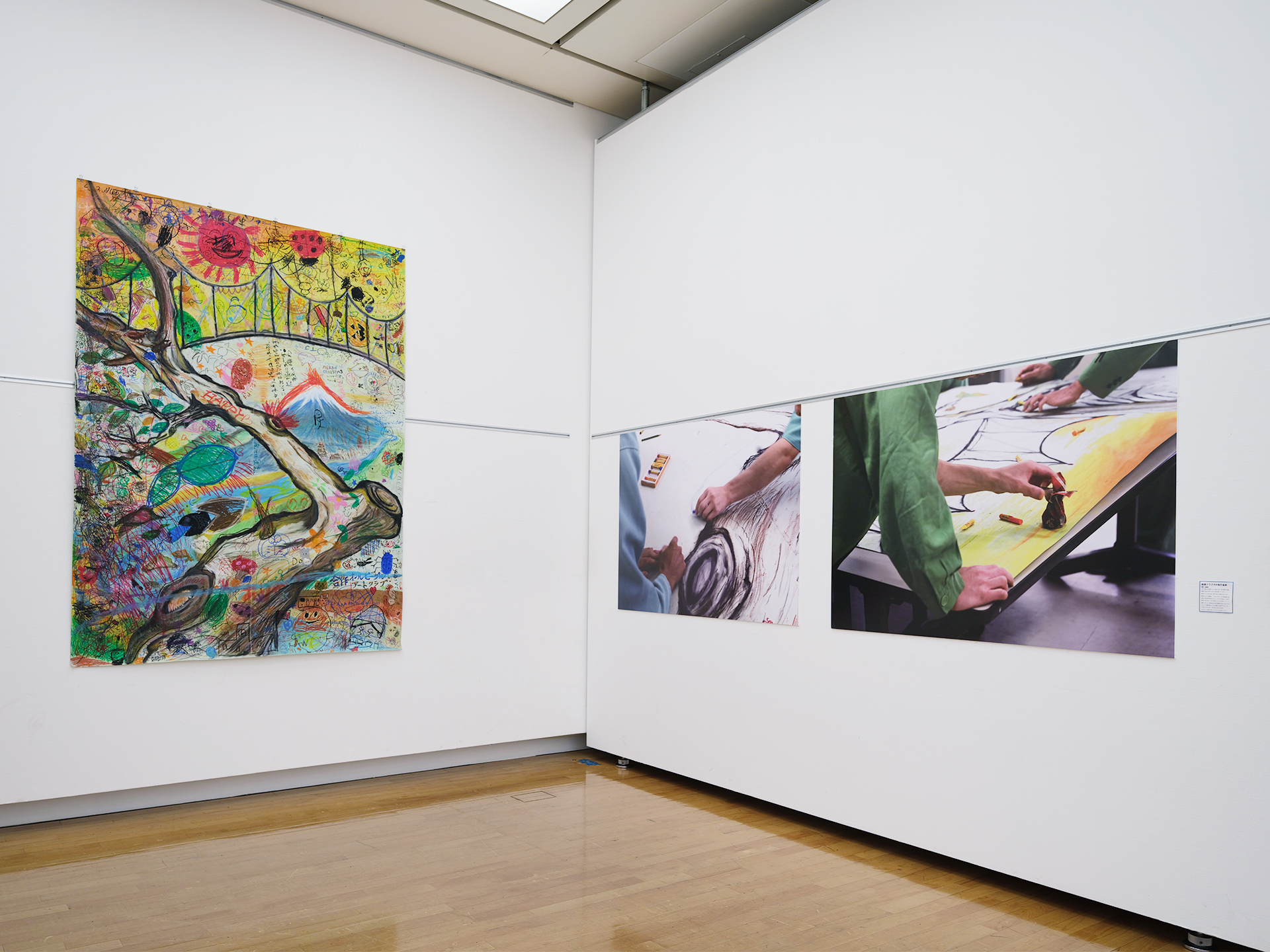 大型絵画「平和と共存」の全体と、共同制作の様子を写した記録写真パネル2点