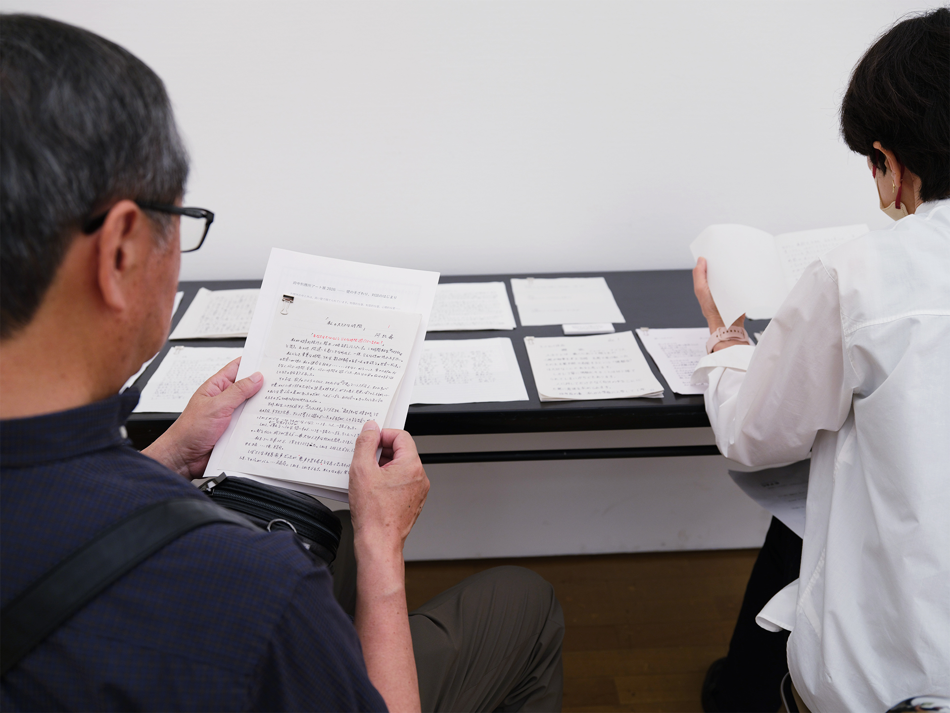 来場者が応募作家からの手紙や作品紹介コメントを手に取って読んでいる様子