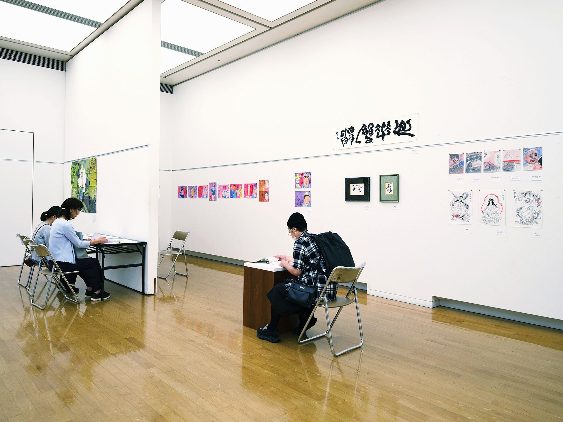 第3部の展示風景。書や水墨画、色紙作品が並ぶ壁面を来場者が鑑賞している様子